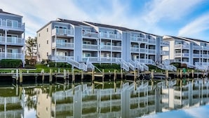 A waterfront apartment complex with multiple balconies and a reflection in the water. - Beautiful 2 BR 2 BA Unit on a Peaceful Canal with a Pool & Views of Fireworks (Ocean City)