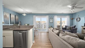 A modern kitchen with a dishwasher, a dining area with a table and chairs, a sofa, and a ceiling fan. - Beautiful 2 BR 2 BA Unit on a Peaceful Canal with a Pool & Views of Fireworks (Ocean City)