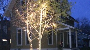 Una casa con un árbol iluminado, un sendero y un porche.
