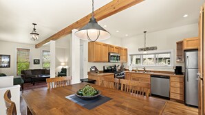 Una cocina moderna con armarios de madera, electrodomésticos de acero inoxidable y un comedor con una gran mesa y sillas de madera.