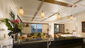 Une chambre d’hôtel avec un coin cuisine, une table à manger et une grande fenêtre donnant sur l’océan.