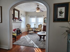 A room with a fireplace, two armchairs, a round table, and a ceiling fan. - 1940s Vintage Home meets comfortable beach retreat (Galveston)