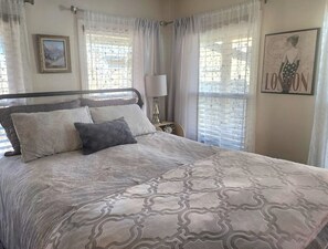 A bedroom with a bed, two pillows, a nightstand with a lamp, and a framed picture on the wall. - 1940s Vintage Home meets comfortable beach retreat (Galveston)