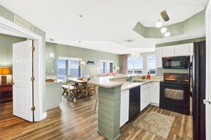 A modern kitchen with a central island, built-in appliances, and a dining area with a view.