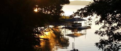 A dock extending into calm water, surrounded by trees.