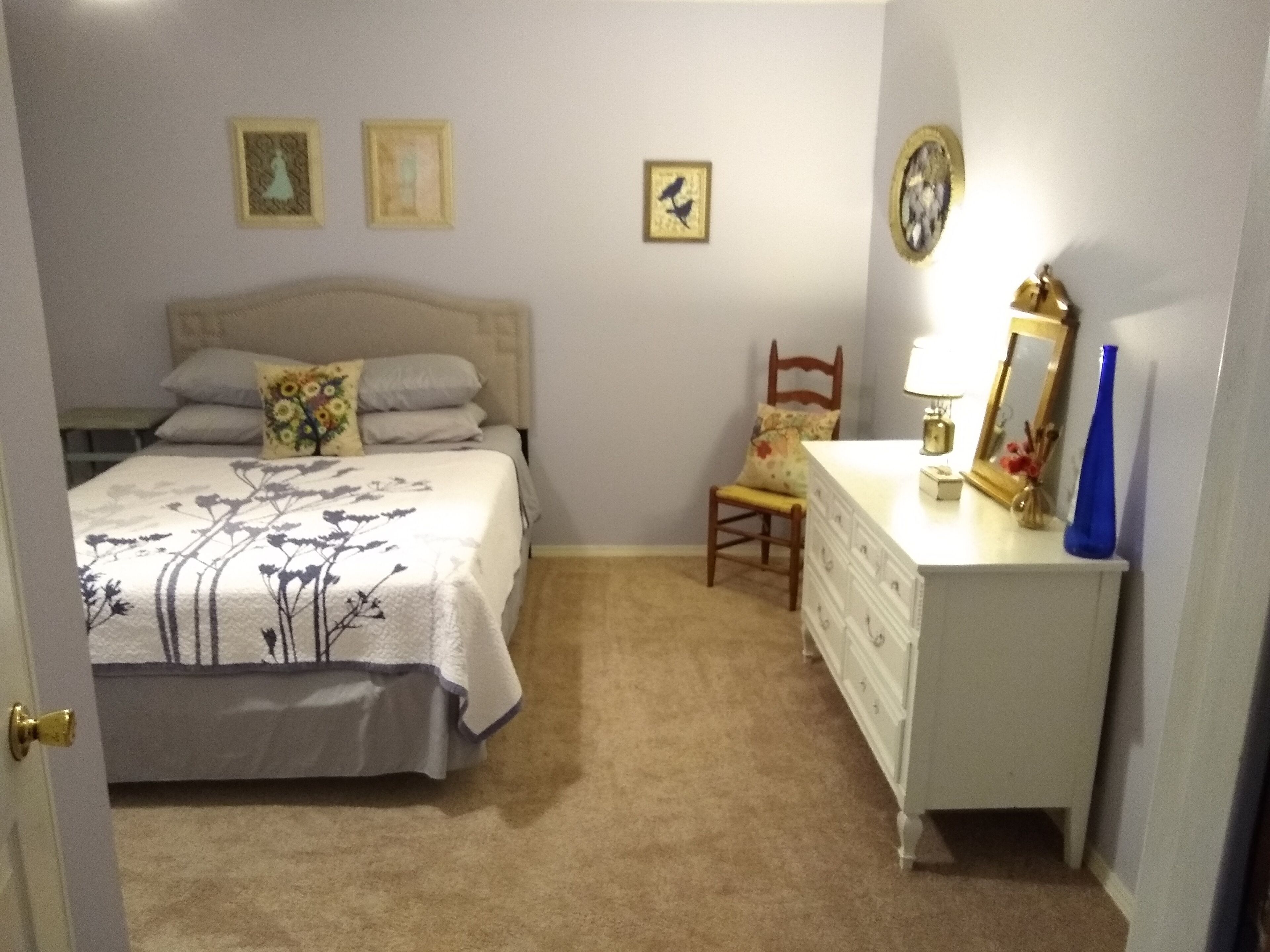 Een slaapkamer met een bed, een kaptafel, een stoel en een nachtkastje.