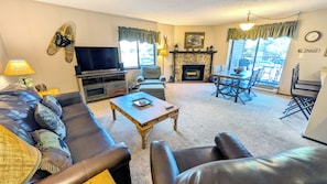 A living room with a sofa, coffee table, TV, fireplace, dining table, and chairs.