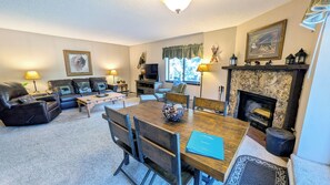 A living room with a fireplace, a dining table, and a sofa set.