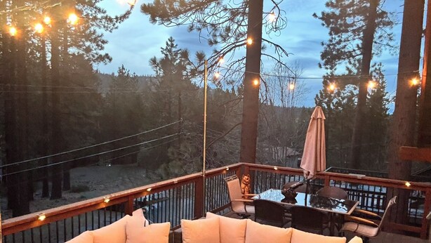 Une terrasse extérieure dotée d’un foyer, de sièges confortables et de guirlandes lumineuses.