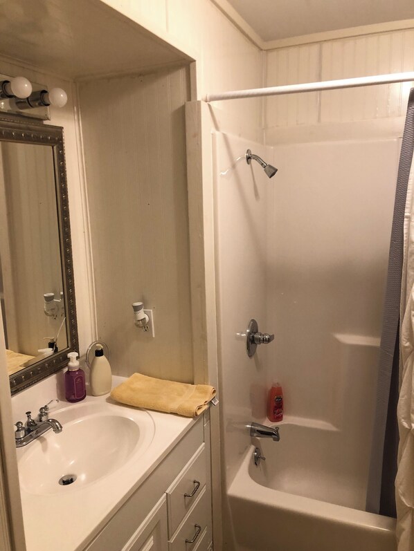 A bathroom with a sink, mirror, and shower.