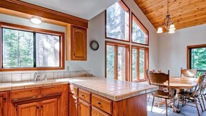 A kitchen with wooden cabinets, a large island, and a dining area with chairs.