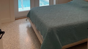 A bedroom with a bed, a ceiling fan, and a view of a pool through the doors. - A GEM-Beach Cottage 4 BR,Heated Pool on Canal, 1 Block To Village, Walk to Beach (Sarasota)