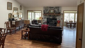 A spacious living room with a fireplace, wooden flooring, and a ceiling fan.