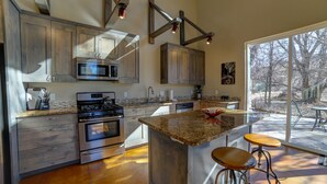A modern kitchen with granite countertops, stainless steel appliances, and a large island with bar stools. - 3B/2B Modern Downtown Moab Townhouse - Short Walk from the Heart of Downtown (Moab)
