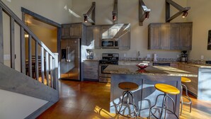A modern kitchen with stainless steel appliances, wooden cabinets, and a central island with bar stools. - 3B/2B Modern Downtown Moab Townhouse - Short Walk from the Heart of Downtown (Moab)