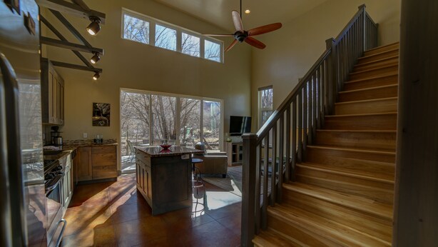 A spacious kitchen with a central island, large windows, and a wooden staircase. - 3B/2B Modern Downtown Moab Townhouse - Short Walk from the Heart of Downtown (Moab)
