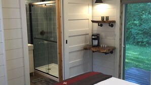 A bedroom with a glass shower, a wooden ceiling, a deer head decoration, and a view of greenery outside. - Hidden Springs on Long Lake  -  Sleeping Bear Dunes National Lakeshore (Honor)