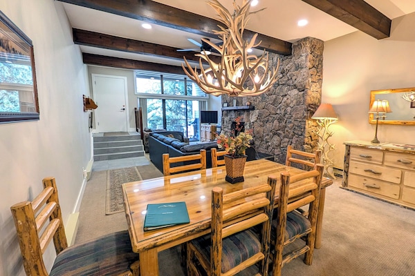 Living room w/ wood fireplace, dining table, and balcony with propane BBQ grill