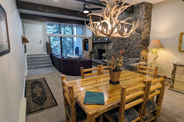 Living room with wood fireplace, dining table, and balcony with propane BBQ