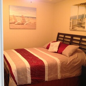 Cozy retreat with a single bed, striped bedspread, and two pillows, complemented by framed artworks above.