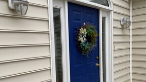 Una porta d'ingresso blu con una ghirlanda, una cassetta delle lettere bianca e un molo in legno.