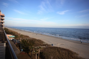 A beach view from a balcony overlooking a sandy beach with a clear sky. - Myrtle Beach Oceanfront Condo with Huge Sundeck Balcony (Myrtle Beach)