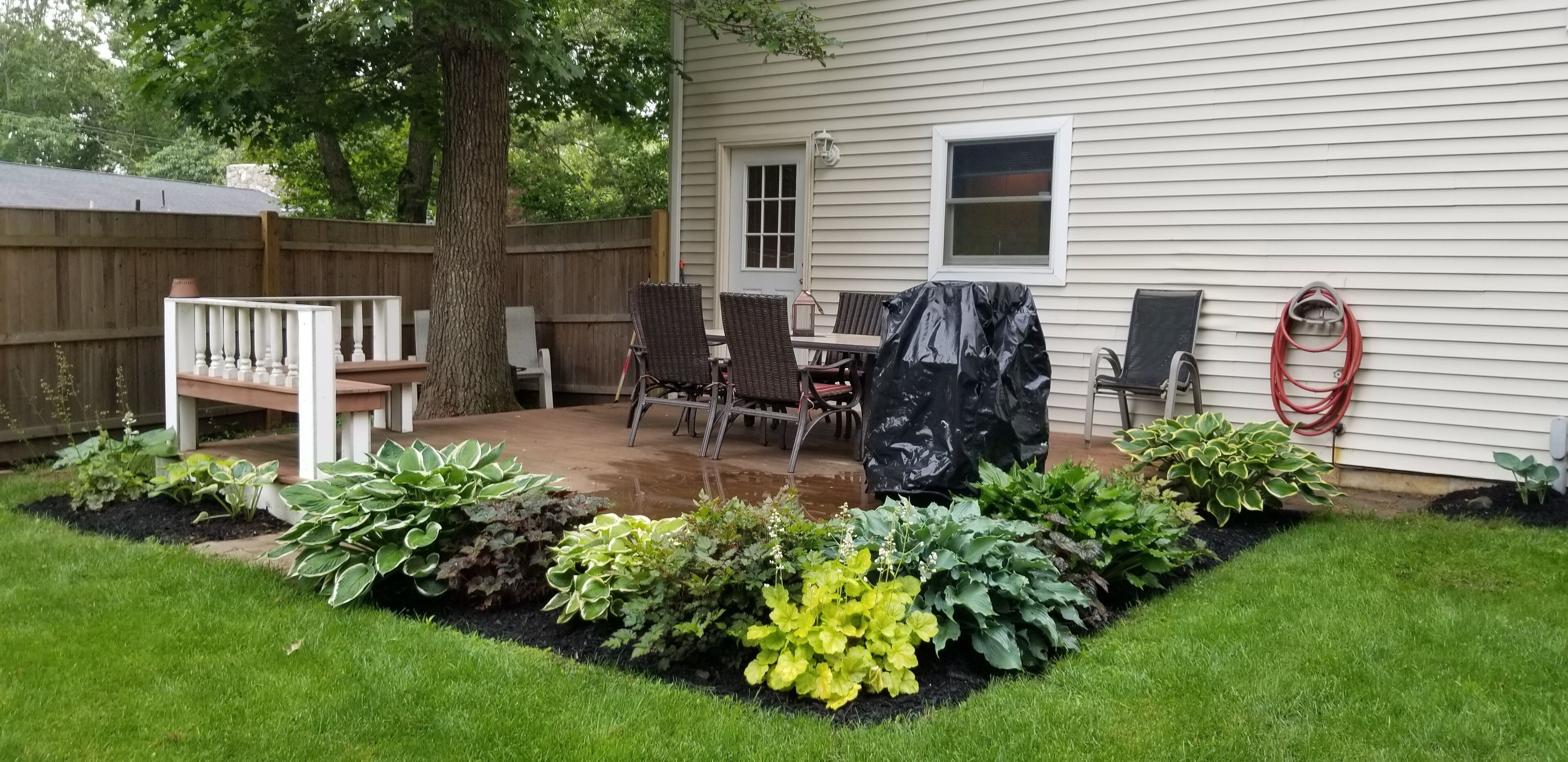 A backyard with a patio, a covered table, and a wooden deck.