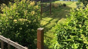 A view of a lake with a wooden deck and lush greenery in the foreground. - Tide Cove Beachhouse in Poulsbo (Poulsbo)