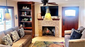 A living room with a fireplace, two sofas with patterned cushions, a coffee table, and a TV on the wall. - Beach1Min Disney25Min Parking W/D Bikes Fast WiFi (Newport Beach)