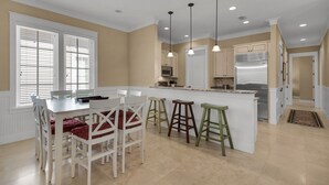 A kitchen with a central island, white cabinetry, and pendant lighting.