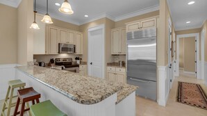 A modern kitchen with a central island, stainless steel appliances, and pendant lighting.