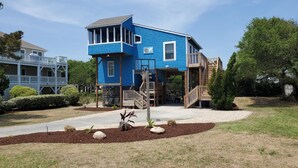 Una casa de dos pisos con fachada azul, un porche cubierto y una pequeña terraza.