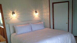 Un dormitorio con una cama grande, dos luces fijadas a la pared y una puerta.