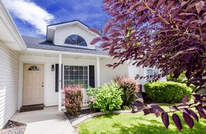 A single-story house with a front porch, a covered entryway, and a small front yard with various shrubs and a tree with purple leaves. - READY IN MERIDIAN.. RELO SPECIALISTS, GOLF COURSE COMMUNITY (Meridian)