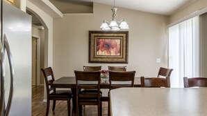 Un coin repas avec une table et des chaises en bois, un lustre et un tableau encadré au mur.