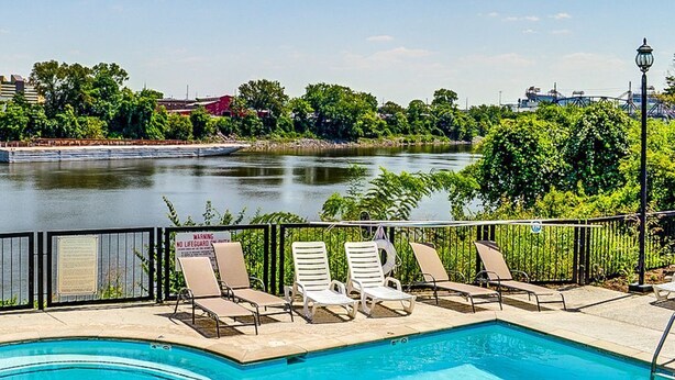 A poolside area with lounge chairs and a view of a lake. - Stunning River View Condo Near Downtown With Free Covered Parking (Nashville)
