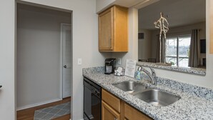 A modern kitchen with granite countertops, stainless steel sink, and wooden cabinets. - Stunning River View Condo Near Downtown With Free Covered Parking (Nashville)
