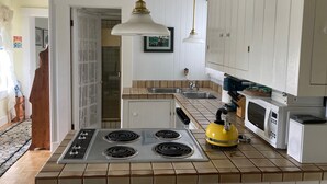 A kitchen with a central island stove, a microwave, and a sink. - Private Garden Cottage In Mendocino's Historic Preservation District (Mendocino)