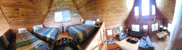 Una cabaña con techo cónico, paredes de madera, una ventana central y un comedor con mesa y sillas.