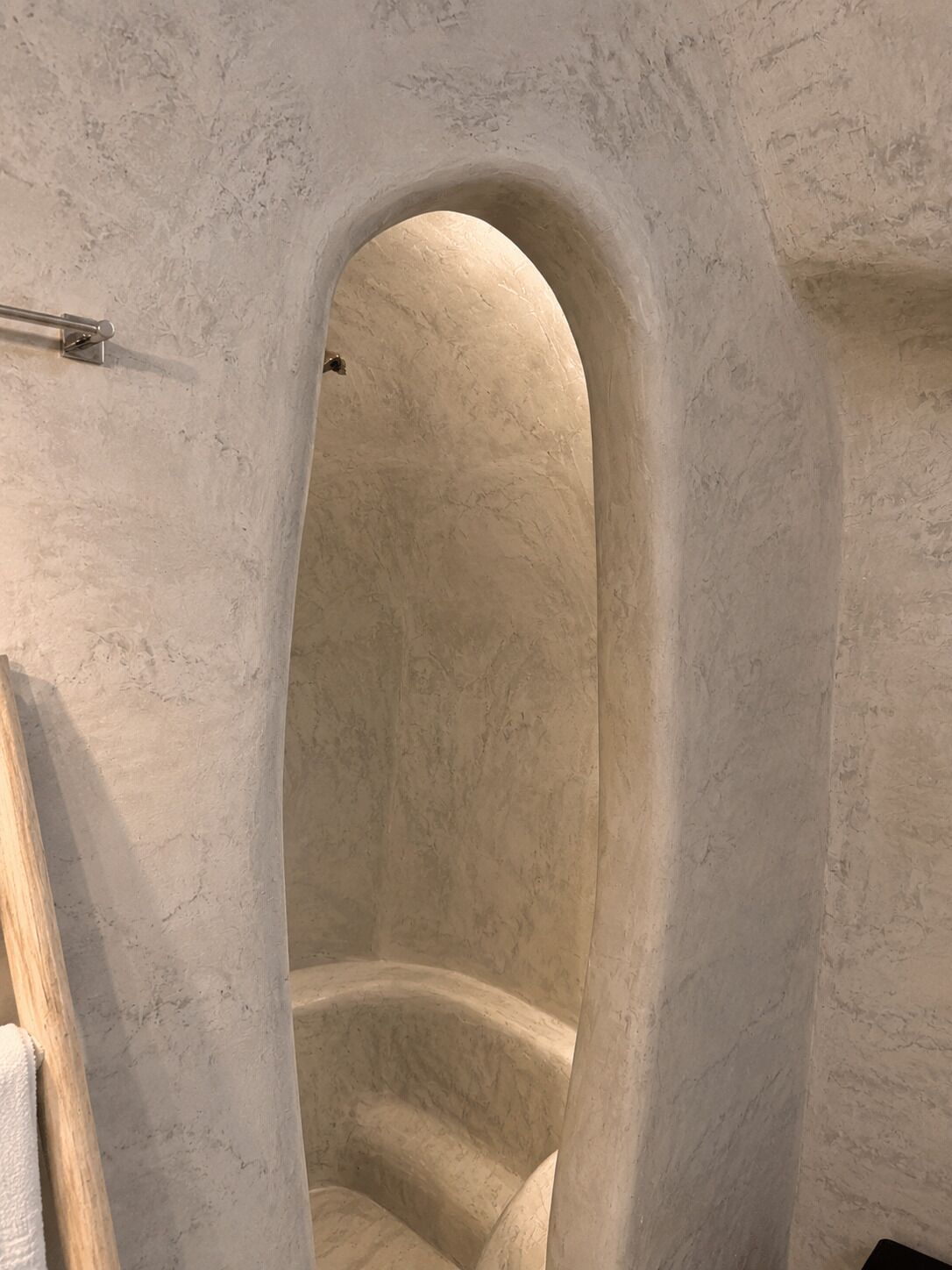 Una habitación con una pared curva y texturizada, y un acceso a otro espacio.