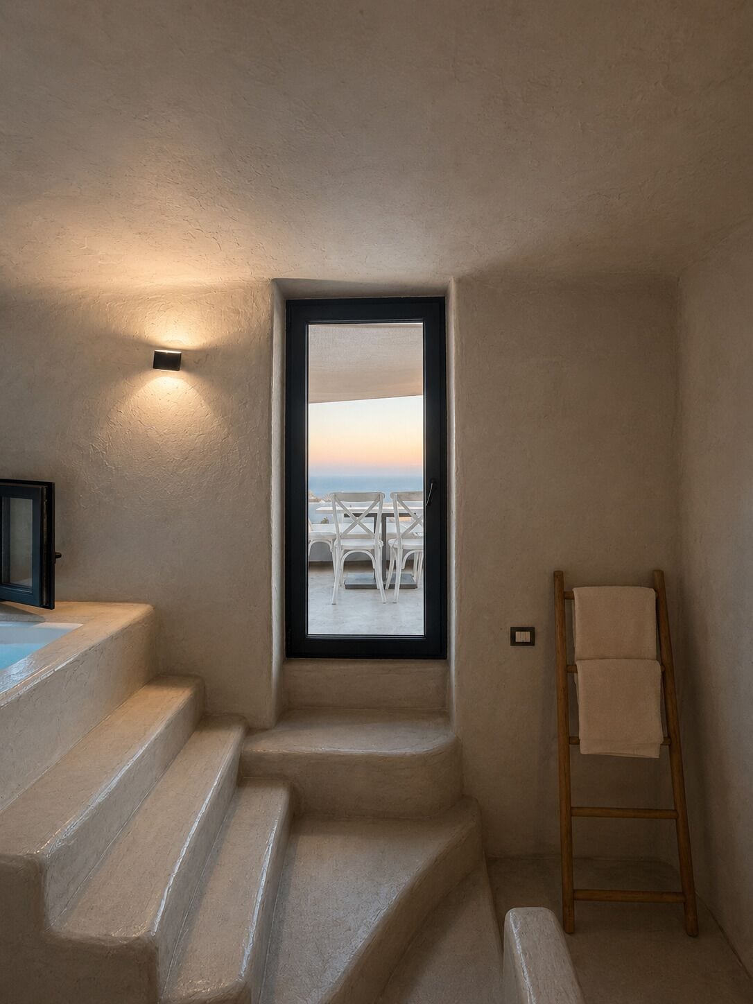 A room with a view of outdoor seating, a wooden ladder, and a light fixture.