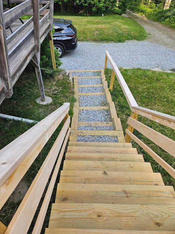 Una escalera de madera que conduce a un sendero de grava, rodeada de vegetación.