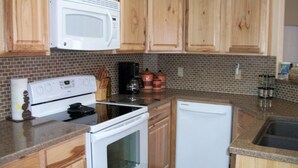 Una cucina con mobili in legno, forno a microonde, piano cottura e lavastoviglie.