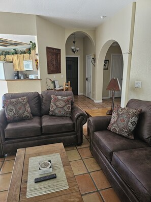 A living room with two brown leather sofas, a wooden coffee table, and a remote control.