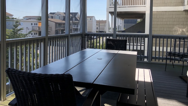 Un patio techado al aire libre con una mesa y sillas, con vista a una zona residencial.