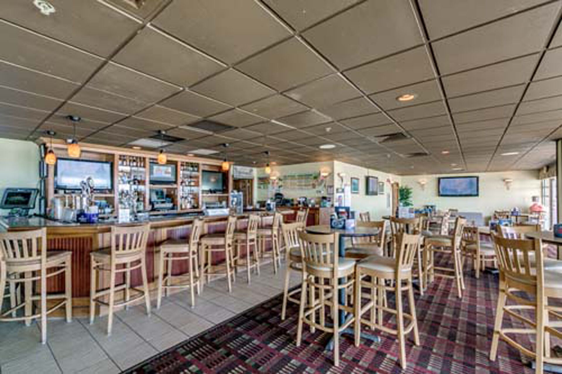 A restaurant with a bar area, multiple seating options, and a patterned floor.