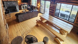 Un chalet confortable avec une cheminée en pierre, une table à manger en bois et une grande fenêtre donnant sur le paysage extérieur.