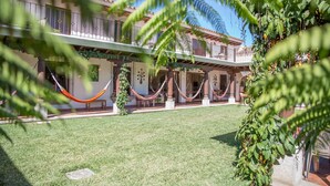 Un cortile con piscina, amache e un edificio con un balcone.