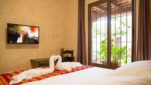 Una camera d'albergo con un letto, una televisione a parete e una finestra con tende.