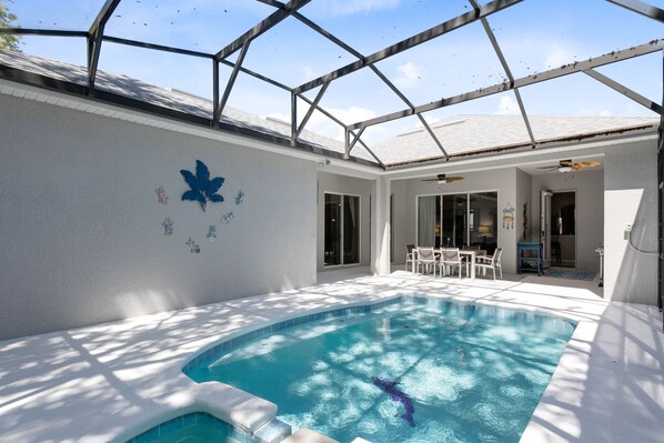 A swimming pool with a glass ceiling, surrounded by a patio area with outdoor furniture.